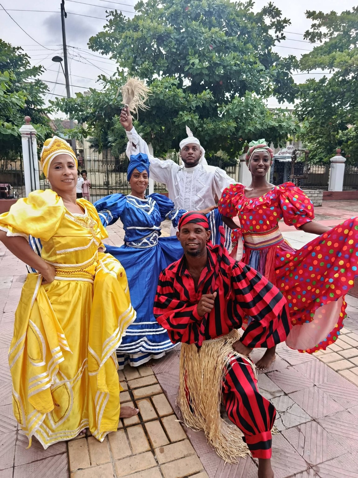 Folklórico Cutumba artists posing outdoors in colorful performance costumes