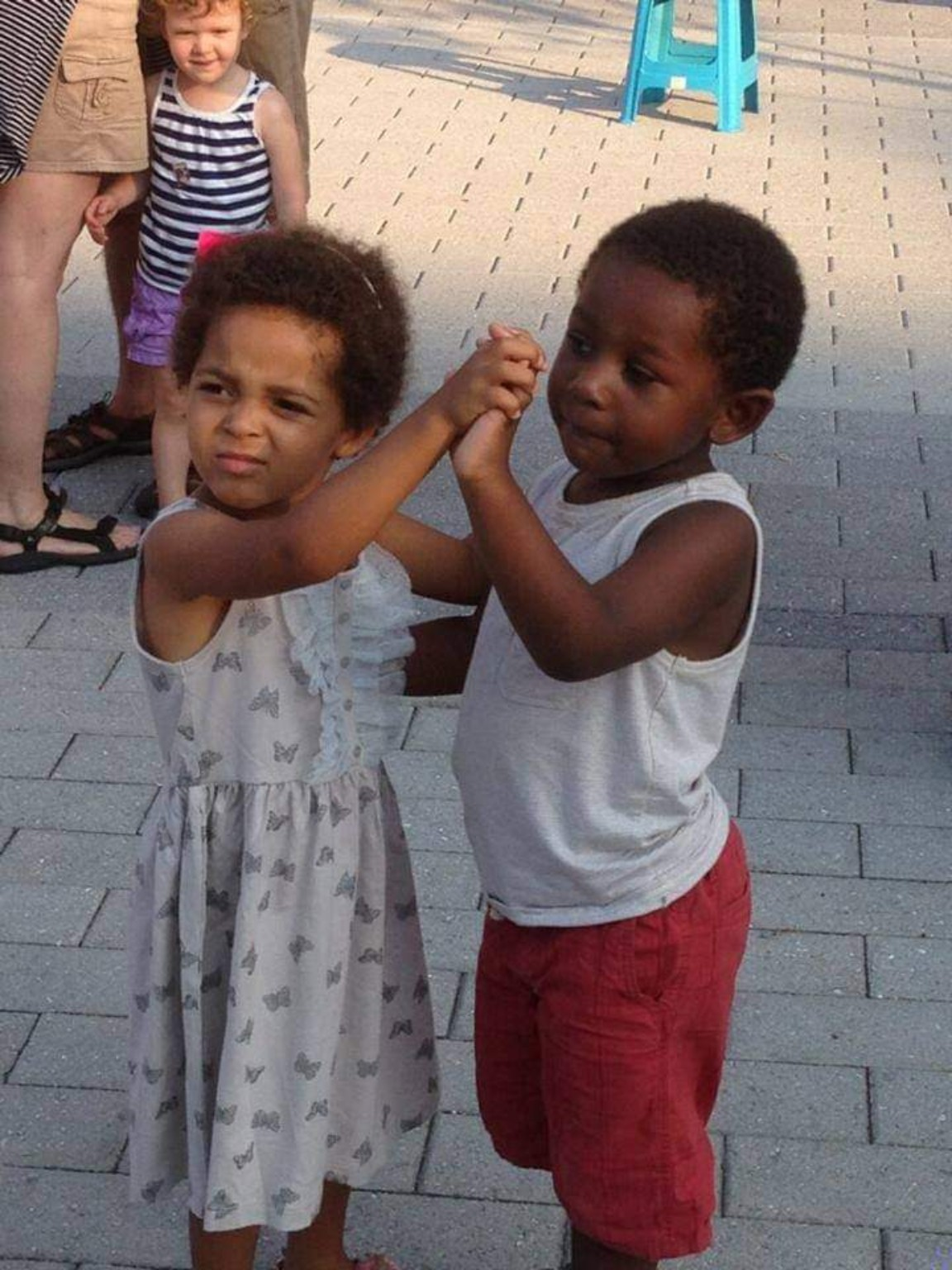 Dos niños tomados de la mano durante una actividad de baile al aire libre en Art on 8th