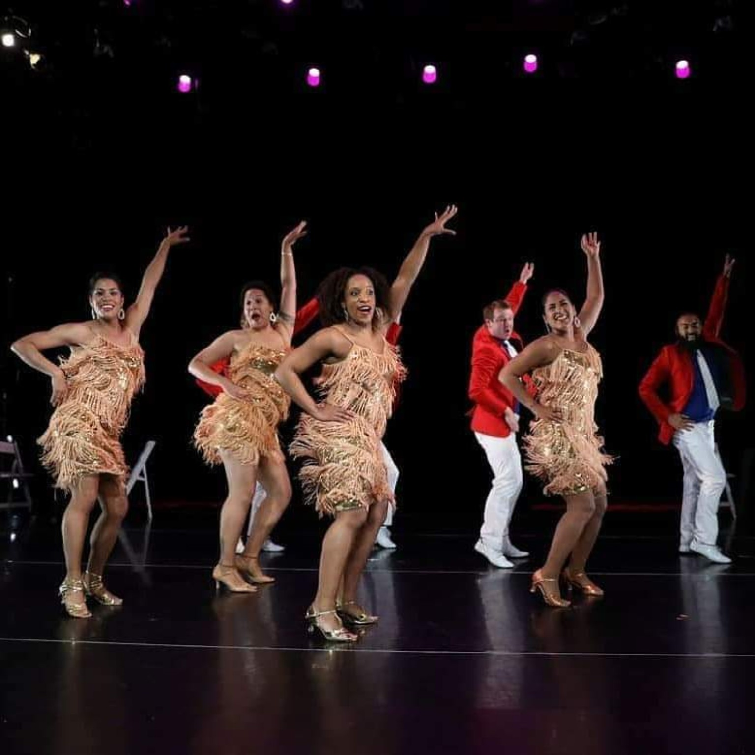 DC Casineros dancers performing in our theater show in gold dresses and red jackets
