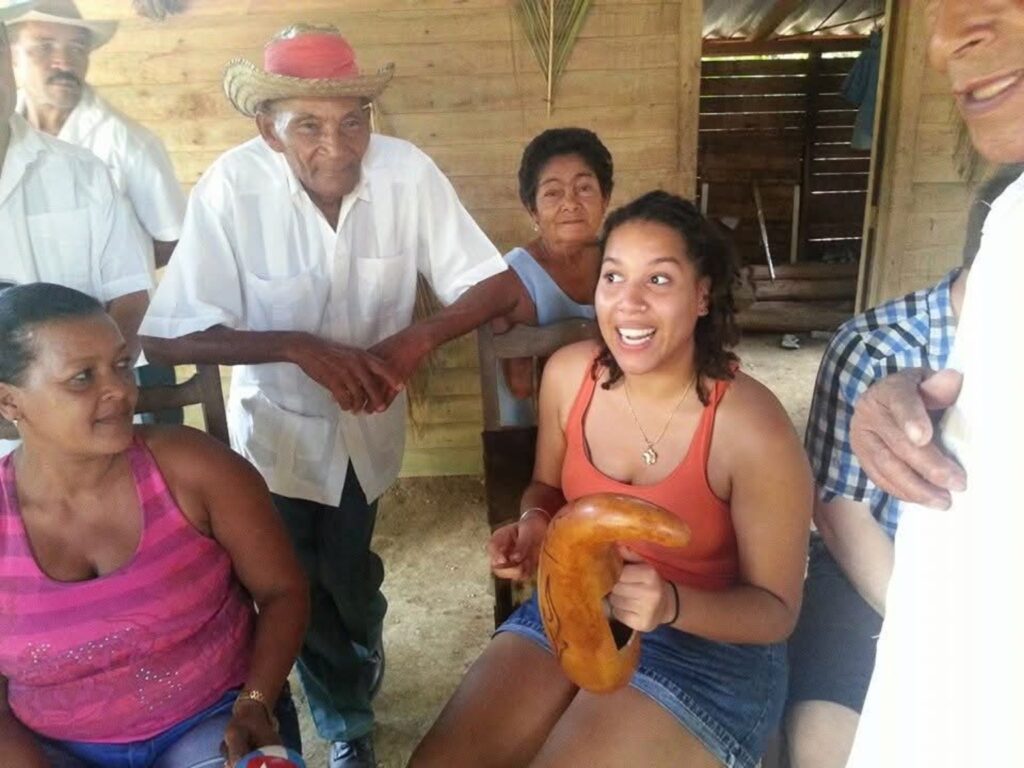 Una visitante con un güiro junto a integrantes de la comunidad durante un intercambio musical en Baracoa