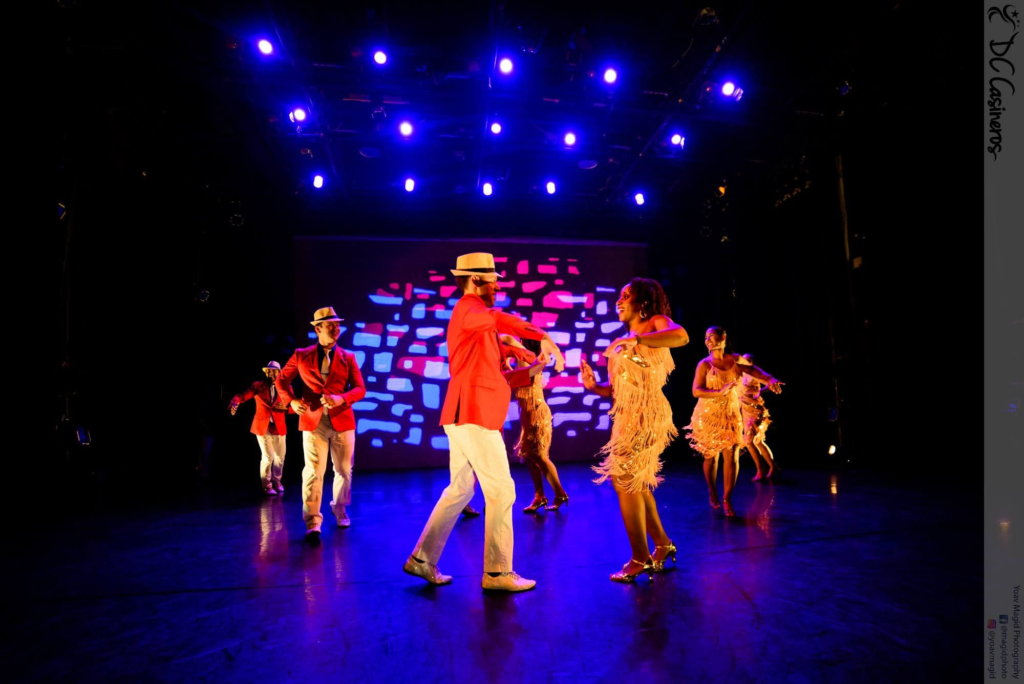 DC Casineros ensemble performing in red jackets, white trousers, hats and fringe dresses