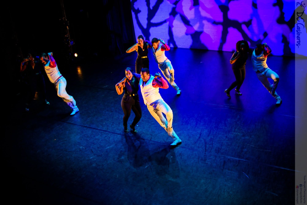 DC Casineros ensemble in white vests and black outfits performing under blue stage lighting