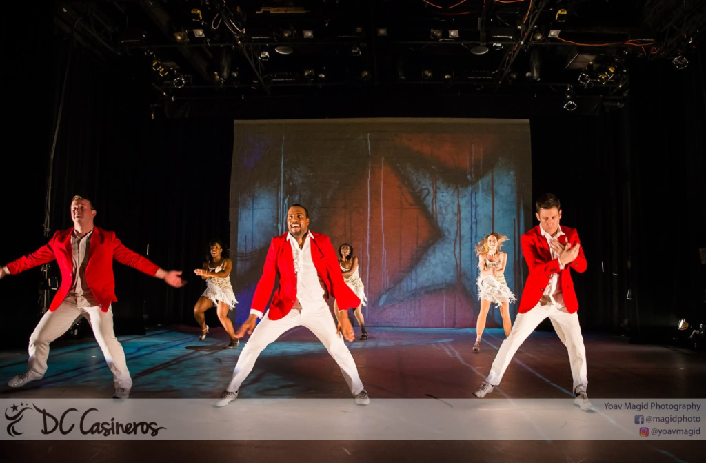 DC Casineros ensemble performing in red jackets and white fringe dresses