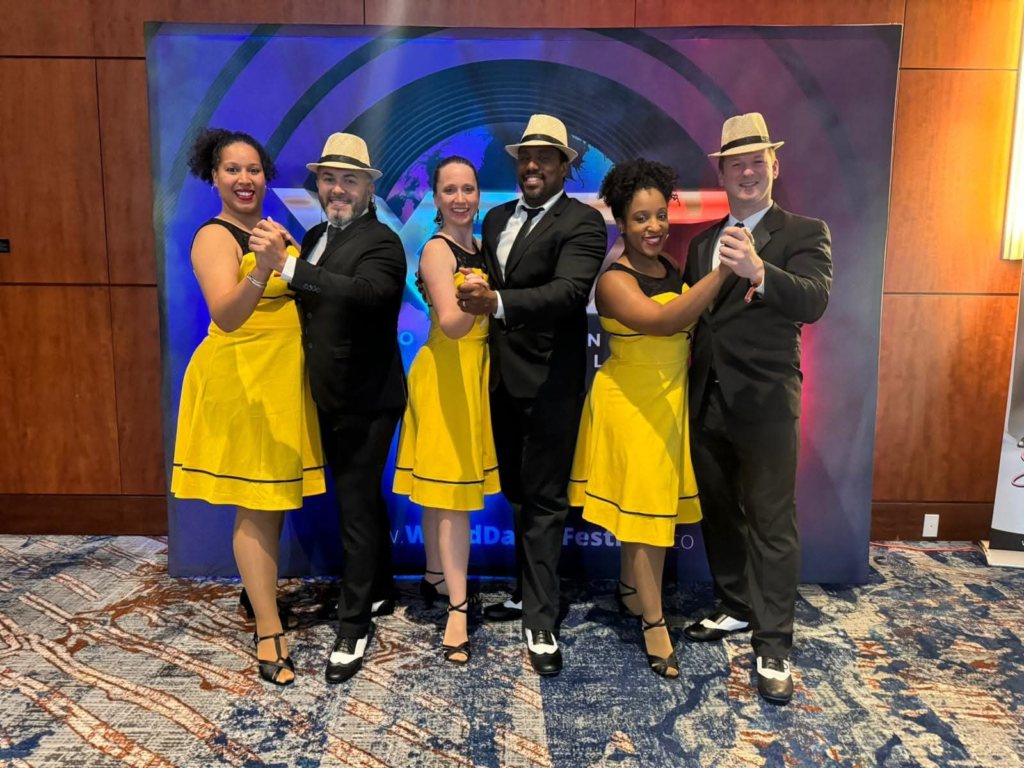 DC Casineros dancers posing in pairs in yellow dresses and black suits