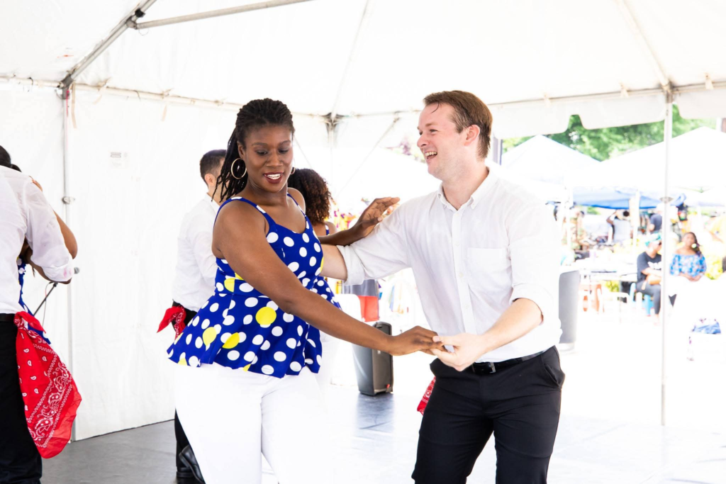 Two dancers enjoying Cuban partner dance beneath an outdoor event tent