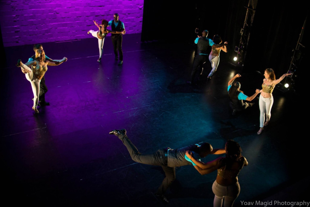 DC Casineros dancers performing coordinated partner balances across a purple-lit stage.