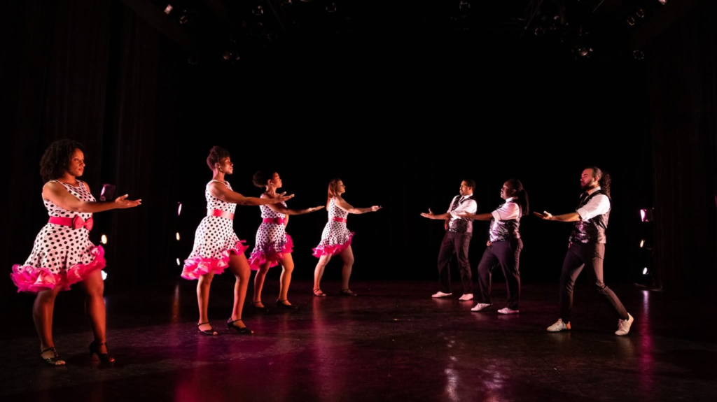 DC Casineros ensemble in polka-dot dresses and sequined vests performing on stage.