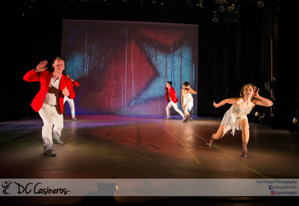 DC Casineros dancers performing on stage in red jackets and white fringe dresses