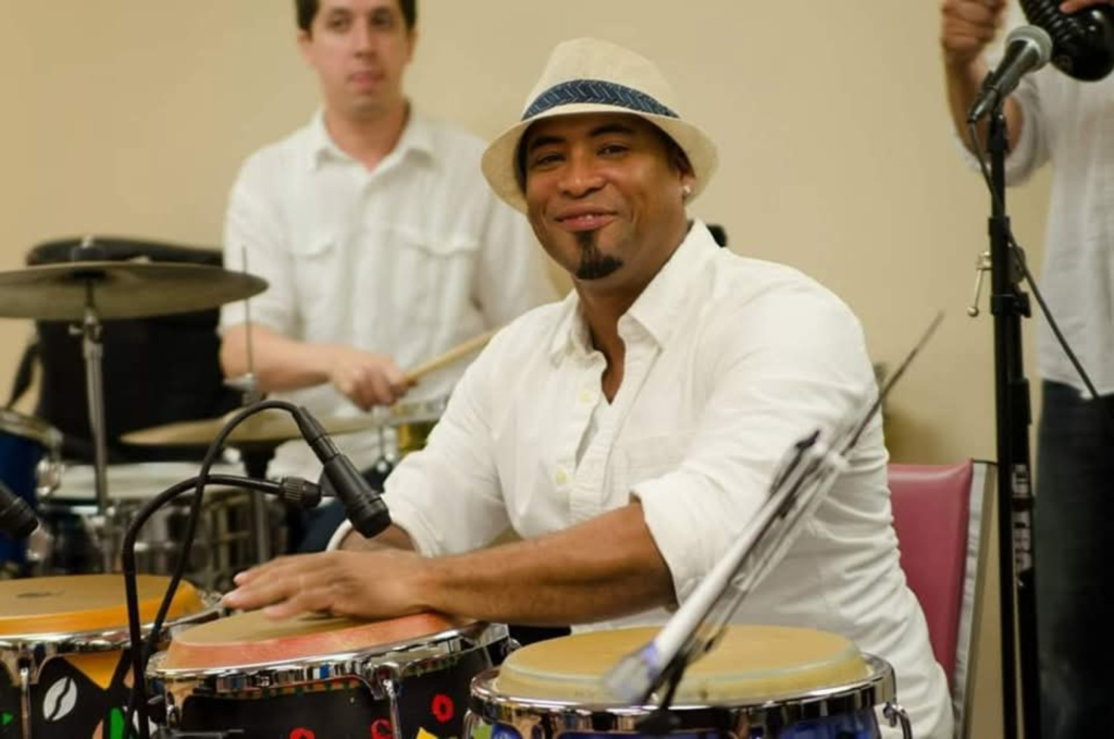 Randell Villalonga smiling while seated at the congas